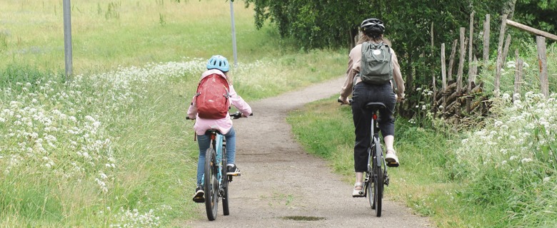 Två personer som cyklar längs en grusväg.