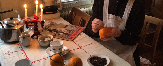 Från köket på Aschanska gården, husan dekorerar apelsiner vid köksbordet.