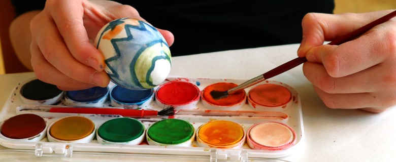Person målar ett påskägg med vattenfärger.