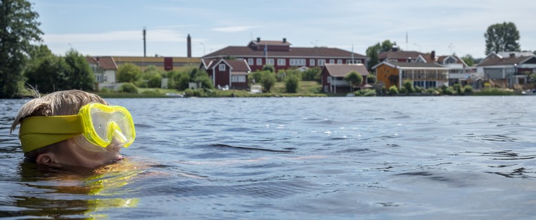 Ett barn som simmar i sjön Hjelten.