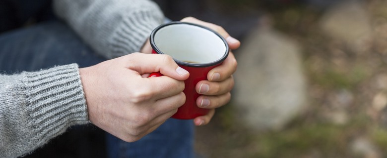 Närbild av två händer som håller i en mugg.