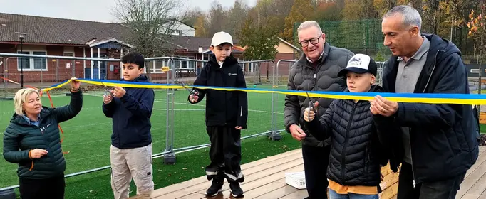 Elever, personal och politiker står på skolgård och elever klipper band.