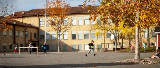 Barn som leker på skolgården och Norrtullskolan i bakgrunden.